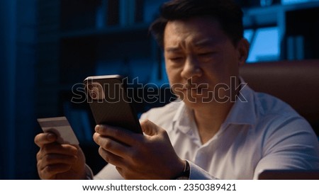 Puzzled confused Asian man failure pay Korean businessman bank credit card online payment problem financial trouble blocked money unsuccessful transaction mobile phone error at night evening office Royalty-Free Stock Photo #2350389421