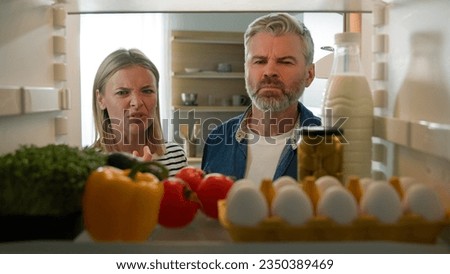 POV Point of view from inside fridge adult couple feeling bad disgusting unpleasant smell from broken refrigerator spoiled rotten food meal middle-aged man and woman awful smelling stink from freezer Royalty-Free Stock Photo #2350389469