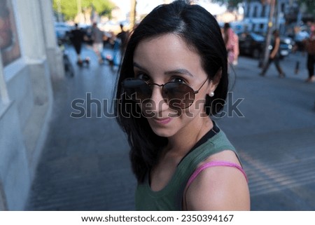 Young woman looking at camera with mischief over glasses. Portrait of young woman smiling african american girl with fashion sunglasses enjoying the city