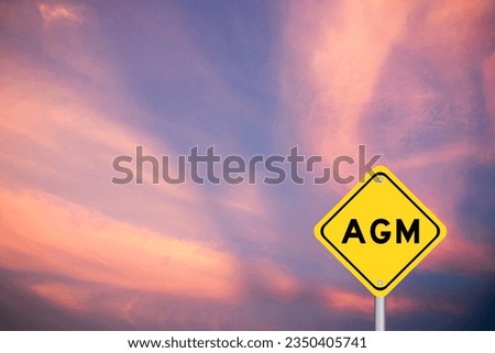 Yellow transportation sign with word AGM (Abbreviation of annual general meeting) on violet color sky background Royalty-Free Stock Photo #2350405741