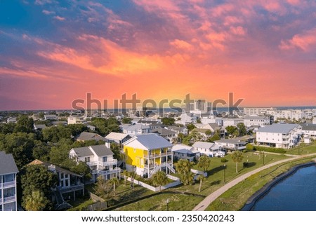 aerial shot of homes along the shores of Carolina Lake with hotels, retail stores and apartments in the city skyline, powerful clouds at sunset and the Atlantic ocean in Carolina Beach North Carolina Royalty-Free Stock Photo #2350420243