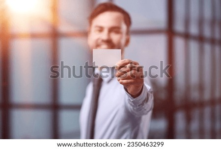 business man holding empty white business card in modern office building. Free blank copy space.