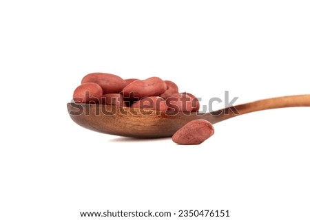 Soft focus on peeled peanuts on a spoon and on a white background.