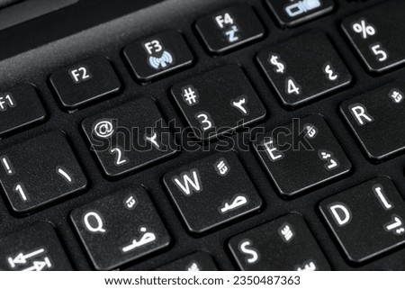 Close up of a QWERTY keyboard english and arabic with letters, figures and symbols, focus on symbol 2