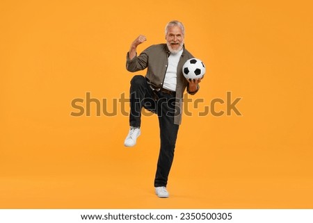 Emotional senior sports fan with soccer ball on yellow background