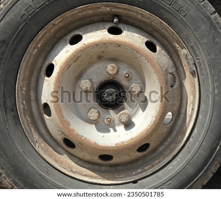 Wheel or automobile disk. View of a gray or silver rim of a car. Fragment of the central part (axle) of an old wheel with fastening bolts. Road dust on car parts. Bolts for fastening a car disk