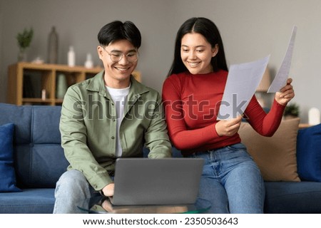 Family Business, Easy Paperwork. Happy young japanese couple with papers using laptop, got mortgage approval, celebrating good online news and reading correspondence together at home Royalty-Free Stock Photo #2350503643