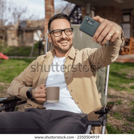 One man happy caucasian male use smartphone for selfie photo or video call outdoor in front of modern tiny house while on vacation holiday in day real people copy space