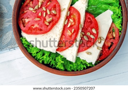 Top view: salad of pickled cheese, tomatoes and roasted sunflower seeds