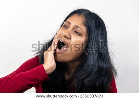A young woman holds her hand to her cheek in pain as she experiences a toothache Royalty-Free Stock Photo #2350507693