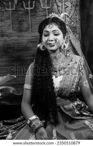 Portrait of beautiful Indian girl of Durga idol Agomoni Concept Indoor Photo. wearing traditional Indian saree, gold jewellery,Maa Durga agomoni shoot concept .Indian culture durga puja