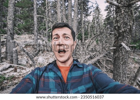 A frightened and lost male hiker looks around in the forest. The concept of meeting wild animals and phobia and accident in the woods Royalty-Free Stock Photo #2350516037