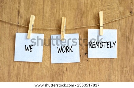 We work remotely symbol. Concept words We work remotely on beautiful white paper on clothespin. Beautiful wooden background. Business we work remotely concept. Copy space.