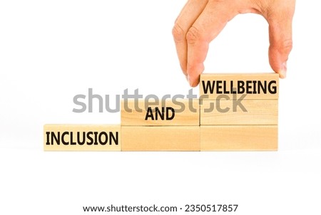 Inclusion and wellbeing symbol. Concept words Inclusion and wellbeing on wooden block. Beautiful white table white background. Doctor hand. Motivational inclusion and wellbeing concept. Copy space.