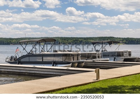 Multiple pontoon boats at marina dock on freshwater lake. Royalty-Free Stock Photo #2350520053