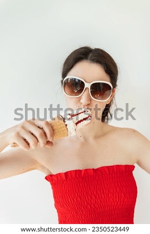Cheerful woman in a bright top and sunglasses eats strawberry ice cream. Selective focus, noise. Summer, vacation, ice cream