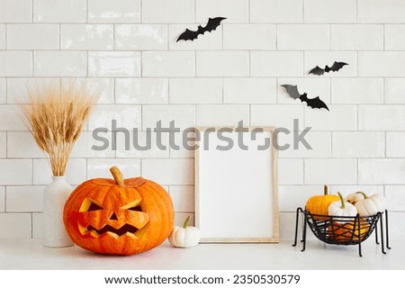 Jack o lantern, Halloween decorations and blank picture frame on brick tile wall background with bats. Happy Halloween concept.