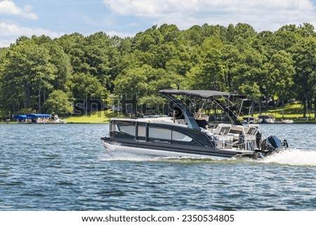 Boaters on pontoon boat enjoying summer day on Lake. Pontoon party boat cruising on freshwater lake. Royalty-Free Stock Photo #2350534805