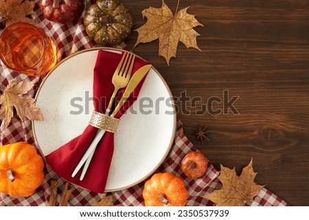 Thanksgiving-inspired table concept. Top view photo of plate, cutlery, tablecloth, cinnamon sticks, pumpkins, autumn leaves, glass on wooden background with empty space for ads or text