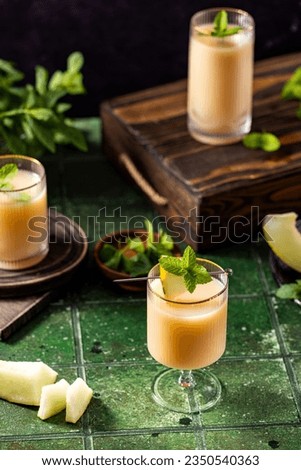 Melon cocktail with mint in glass on dark green ceramic tile background, close up. Summer autumn drinks and alcoholic cocktails. Alcoholic cocktail or detox drink