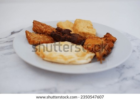 Fried tofu with fried egg and peanut sauce on white marble table