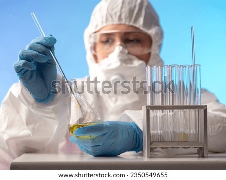 Chemist with flask. Laboratory assistant in chemical protection suit. Virologist is holding test tube. Chemist is experimenting with toxic liquids. Scientist conducts scientific experiment Royalty-Free Stock Photo #2350549655