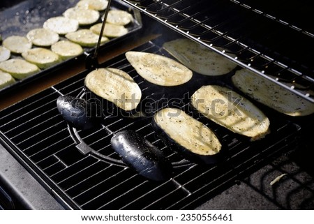 Close-up of spiced ​​zucchini and eggplant slices on a gas grill taken in evening light.  Summer evening vegetarian dinner.  Homemade food concept. Cooking, cookery, gastronomy. Royalty-Free Stock Photo #2350556461