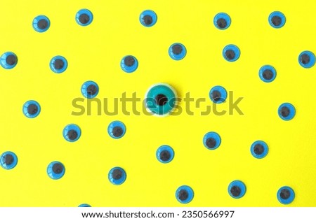 Funny googly blue eyes on a yellow background. Plastic decorative blue eyes. Top view. 