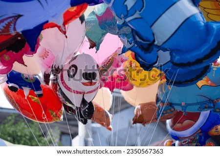 a bunch of flying balloons with lots of characters, hello Kitty, Spiderman, panda, shark, fish and cow