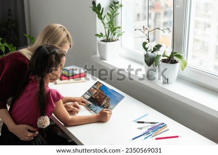 Mother and daughter looking photo book at home.