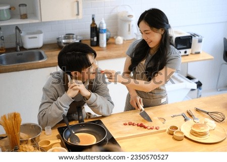 Cute young couple eating preparing breakfast together in kitchen, enjoying leisure weekend time together