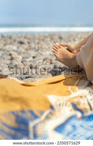 Vertical cropped photo of an unrecognizable latin woman massaging the foot on a beach