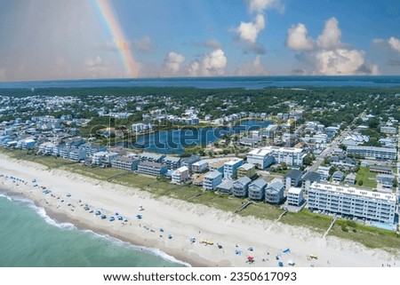 aerial shot of the coastline with green ocean water, waves, people on the beach, homes along the shore, Carolina Lake and lush green trees and grass in Carolina Beach North Carolina USA