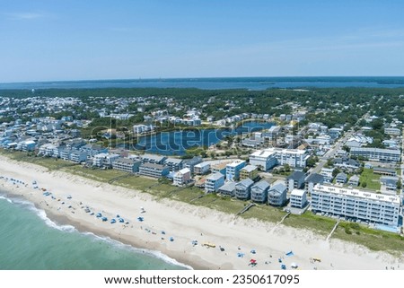 aerial shot of the coastline with green ocean water, waves, people on the beach, homes along the shore, Carolina Lake and lush green trees and grass in Carolina Beach North Carolina USA Royalty-Free Stock Photo #2350617095