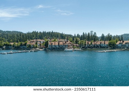 aerial shot of a gorgeous summer landscape at Lake Arrowhead Village with rippling blue water, boats sailing, boat docks and mountains covered in lush green trees in Lake Arrowhead California USA