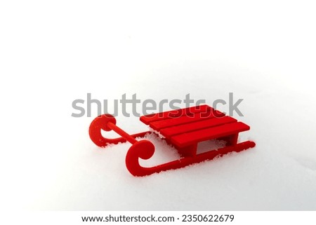 Small Red sled on snow background in beautiful winter day. Copy space for text. Mock up for product greeting card or wallpaper. Christmas