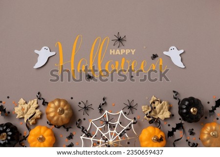 Halloween background with party decorations from pumpkins, bats, spider web and ghosts top view. Holiday greeting card with text insription Happy halloween.
