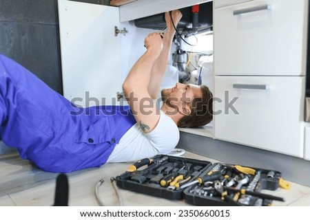Plumber installs or change water filter. Replacement aqua filter. Repairman installing water filter cartridges in a kitchen. Installation of reverse osmosis water purification system Royalty-Free Stock Photo #2350660015