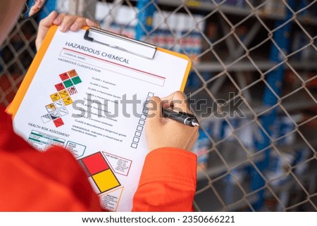 A worker is checking on the hazardous chemical material information form with background of chemical storage area at the factory place. Industrial safety working action. Selective focus. Royalty-Free Stock Photo #2350666221