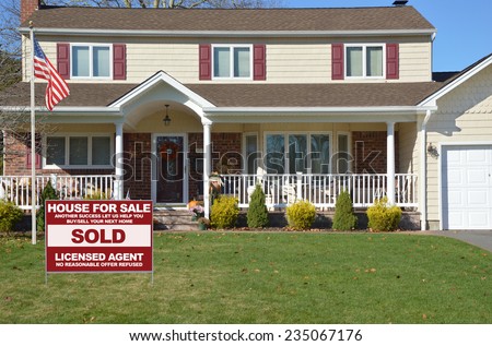 American flag pole Real Estate sold (another success let us help you buy sell your next home) sign Suburban high ranch style home residential neighborhood USA