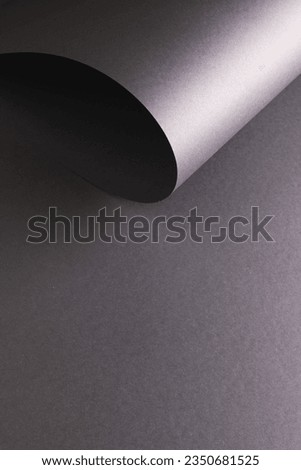 Vertical image of close up of rolled up piece of black paper with copy space on black background. Paper, writing, texture and materials concept.