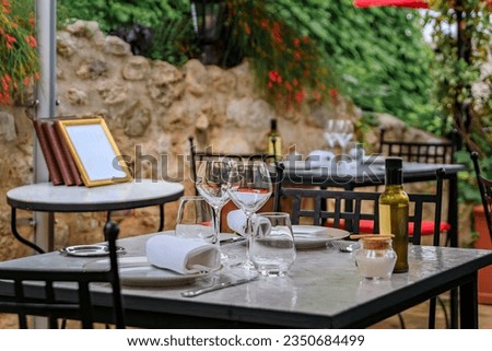 Al fresco tables waiting for customers at an outdoor restaurant in the medieval town of Saint Paul de Vence, French Riviera, South of France Royalty-Free Stock Photo #2350684499