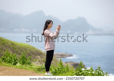 Woman use mobile phone of the take photo beside the sea