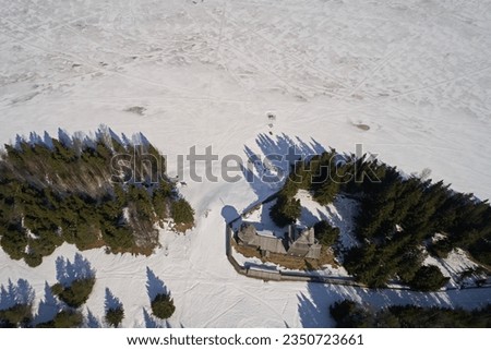 Aerial view of the old orthodox church in the forest in winter. Photo of northern wooden architecture from the drone