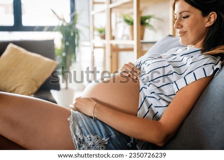 Pregnancy, rest, people and expectation concept. Happy pregnant woman touching her belly at home