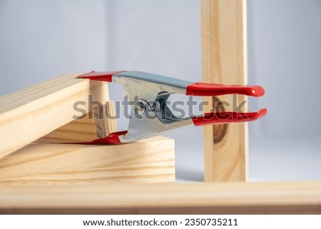 red handled heavy duty srping clip clamp holding two pieces of wooden board together Royalty-Free Stock Photo #2350735211