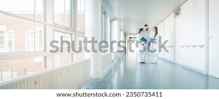Three doctors on hospital corridor having short meeting