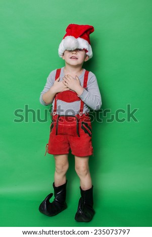 Little beautiful boy with Christmas gnome costume. Studio portrait over green background