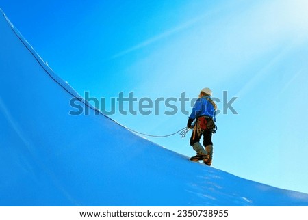 A climber reaching the summit of mountain peak Royalty-Free Stock Photo #2350738955