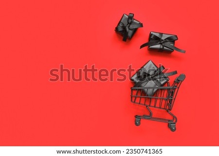 Shopping cart with black gift boxes on red background. Black Friday concept